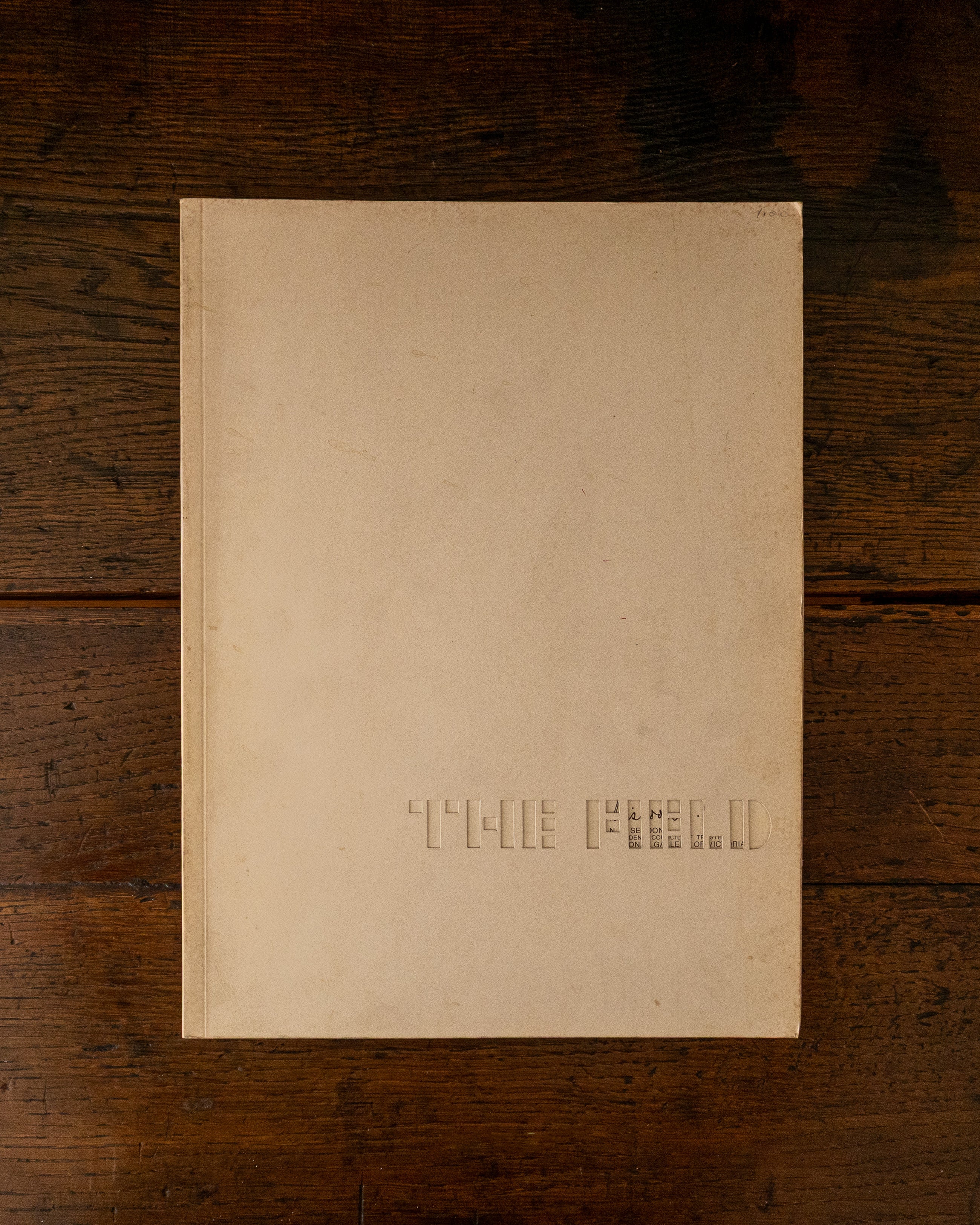 Cover book with embossed text 'The Field' on a wooden surface