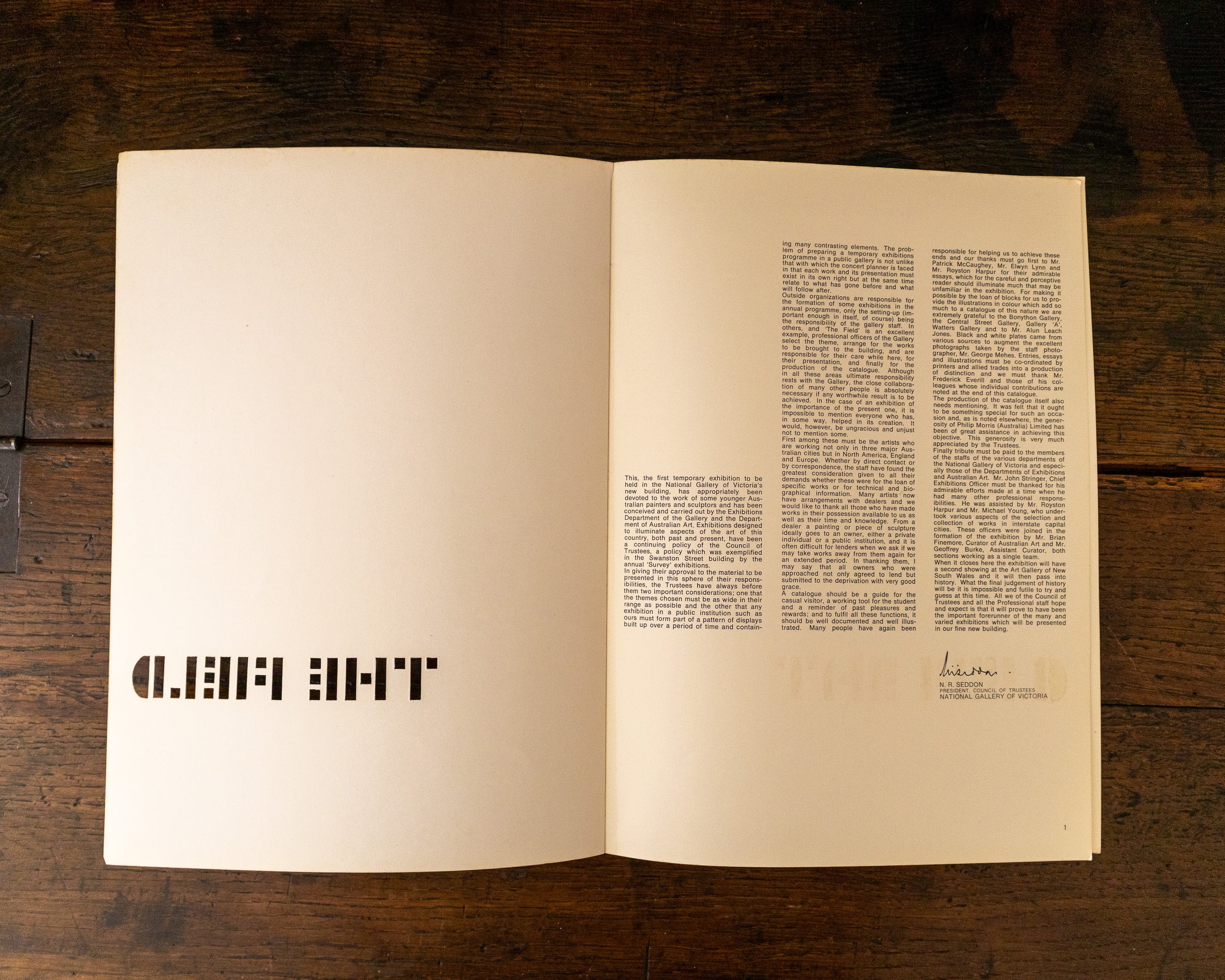 Open book on a wooden surface with text and a logo.