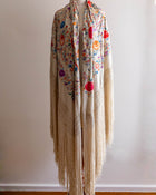Floral patterned scarf with fringe on a mannequin against a plain background