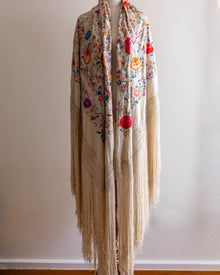 Floral patterned scarf with fringe on a mannequin against a plain background