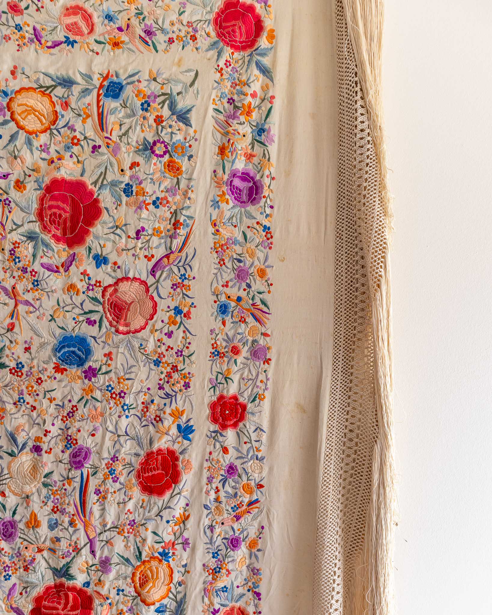 Embroidered fabric with colorful floral patterns on a plain background
