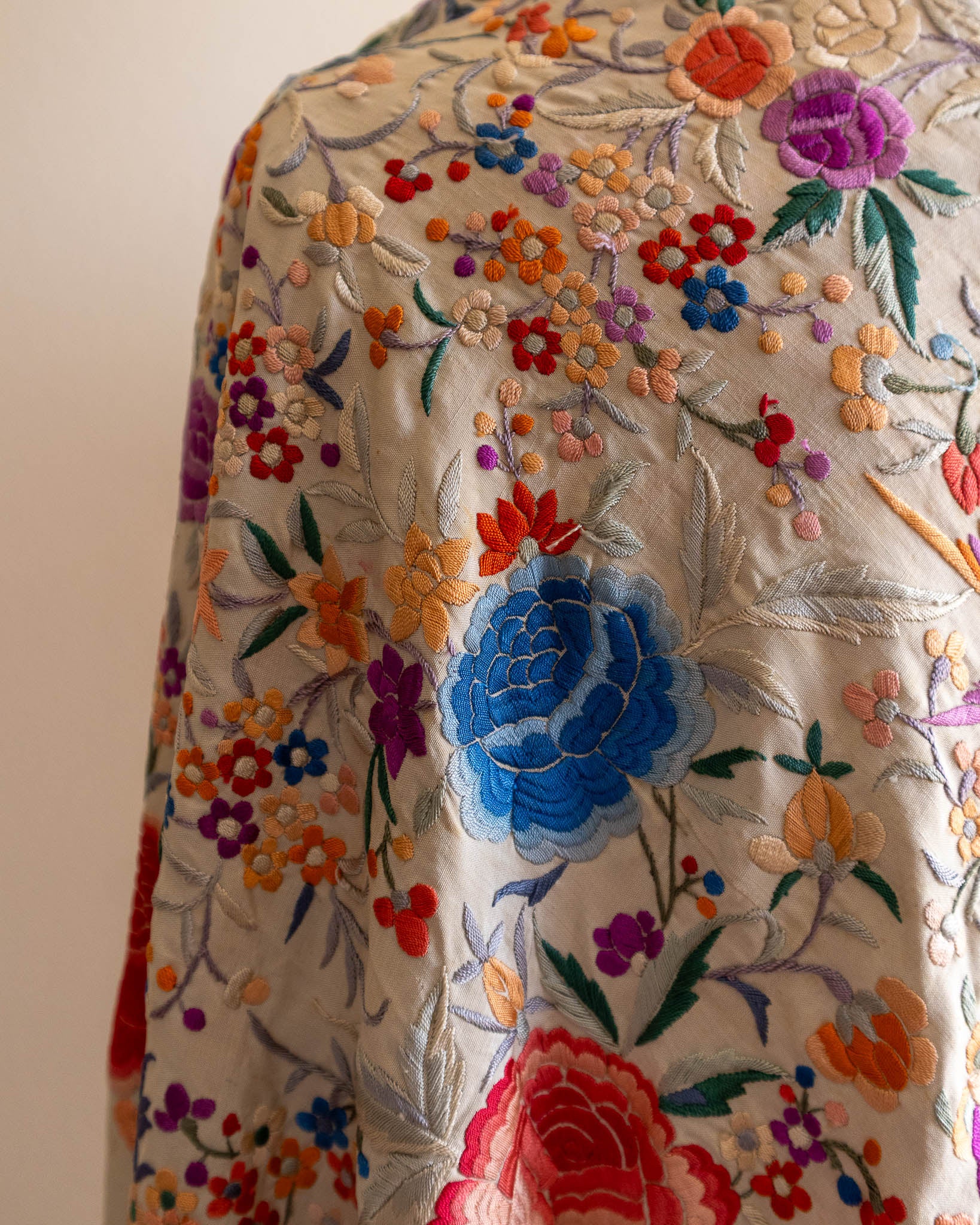 Close-up of a fabric with colorful floral embroidery on a plain background