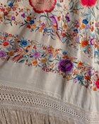 Embroidered fabric with colorful floral and bird patterns on a white background.