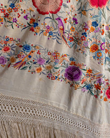 Embroidered fabric with colorful floral and bird patterns on a white background.