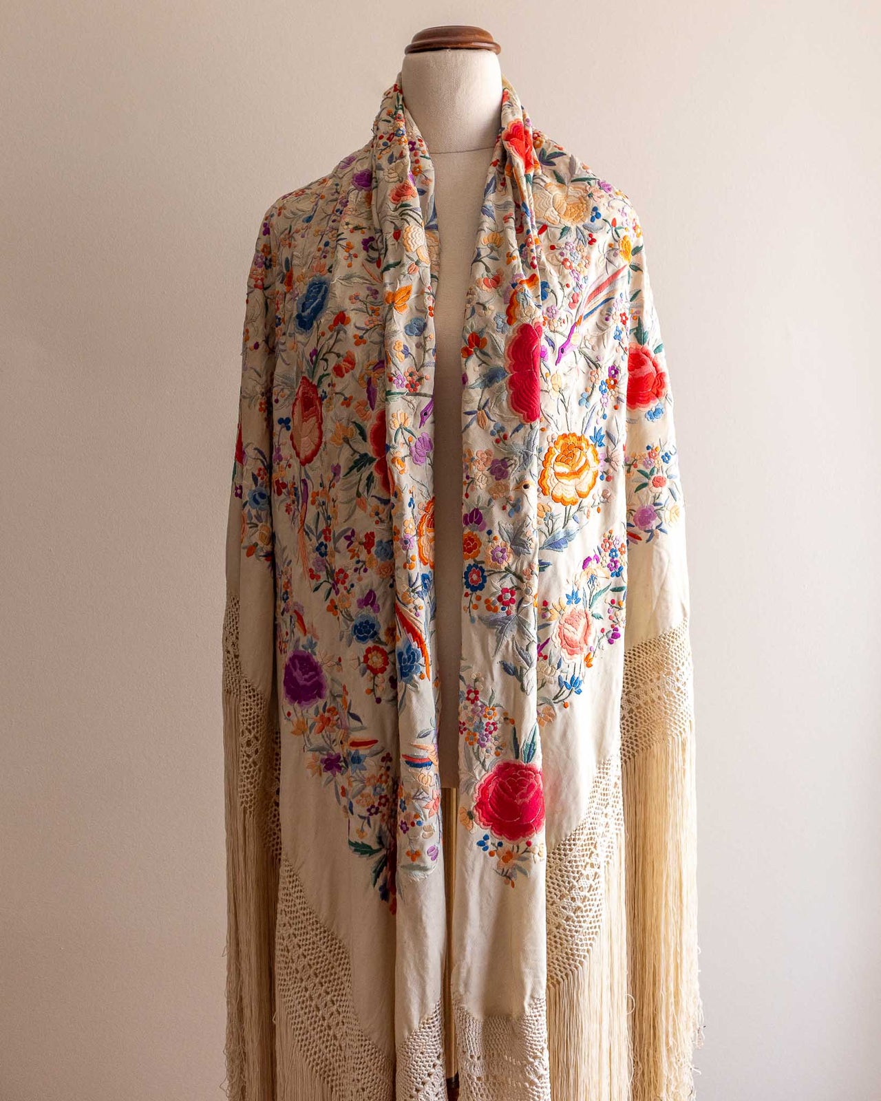 Colourful floral scarf on a mannequin against a plain background