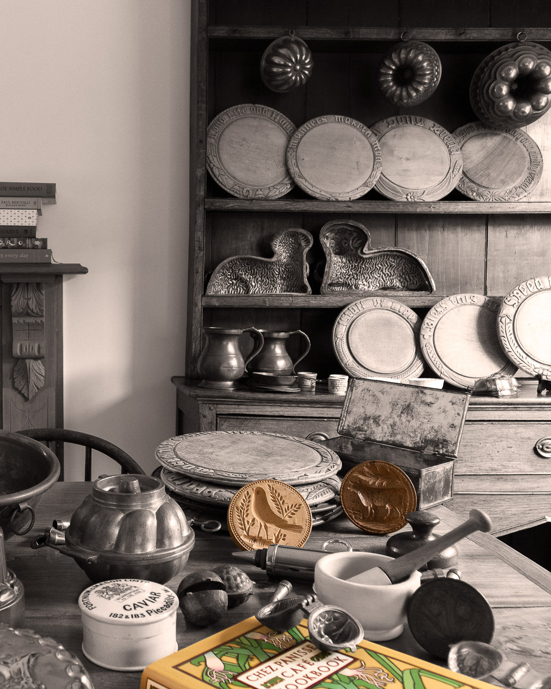 Collection of kitchen items on a table including breadboards, butter stamps, copper moulds and a cookbook